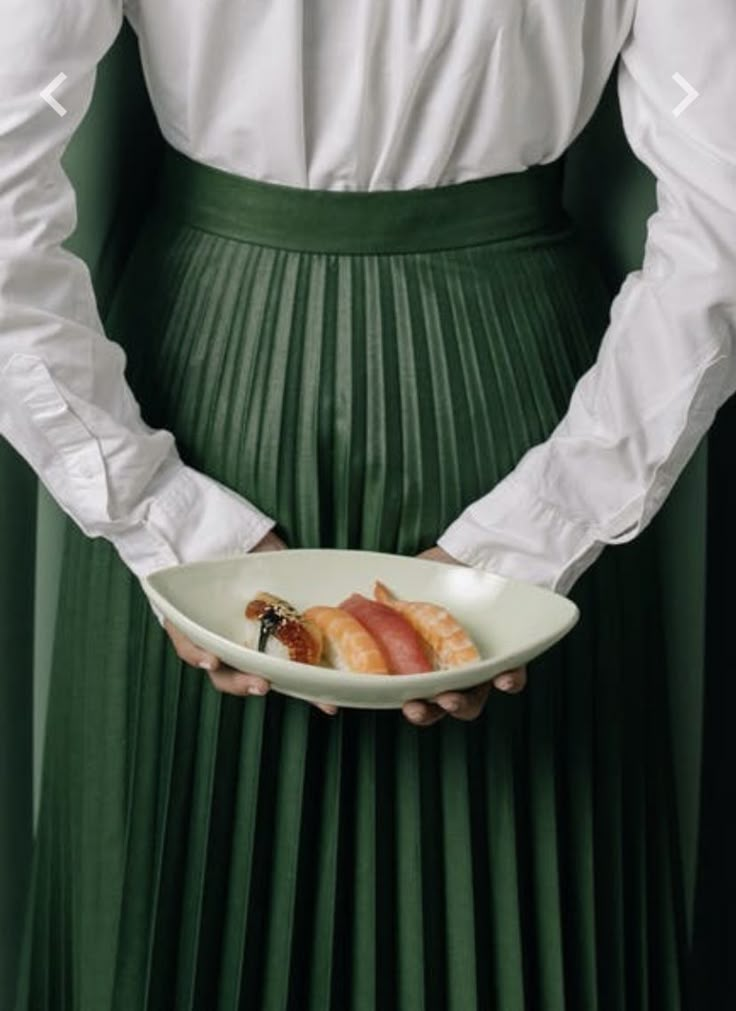 a person in a green skirt holding a plate with food on it's side