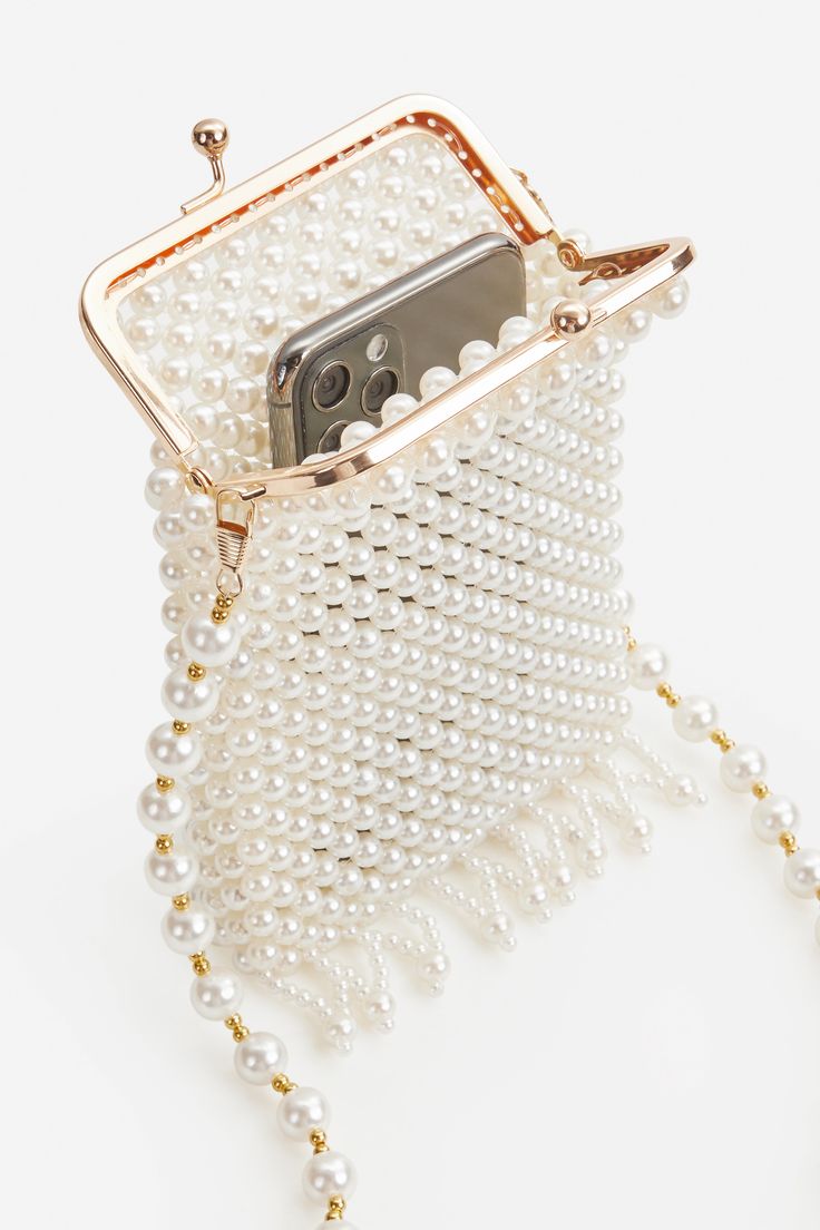 This regal and elegant clutch is completely wrapped in party-ready embellished rhinestones detailing, which sets the stage for a Roaring 20s party. Features: High quality imitation pearls Detachable chain length: 45.3 inch / 115 cm Unique kiss lock closure 3 inch / 13.5 cm x 6.5 inch / 16.5 cm ( L x H ) Chic Pearl Clutch For Party, Elegant Event Clutch With Chain Detail, Gold Pearl Clutch For Parties, Chic Pearl Clutch For Formal Occasions, Pearl Beaded Evening Bag For Formal Occasions, White Pearl Evening Bag For Party, Glamorous Pearl Clutch For Formal Occasions, Glamorous Pearl Clutch For Formal Events, Formal Beaded Pearl Evening Bag