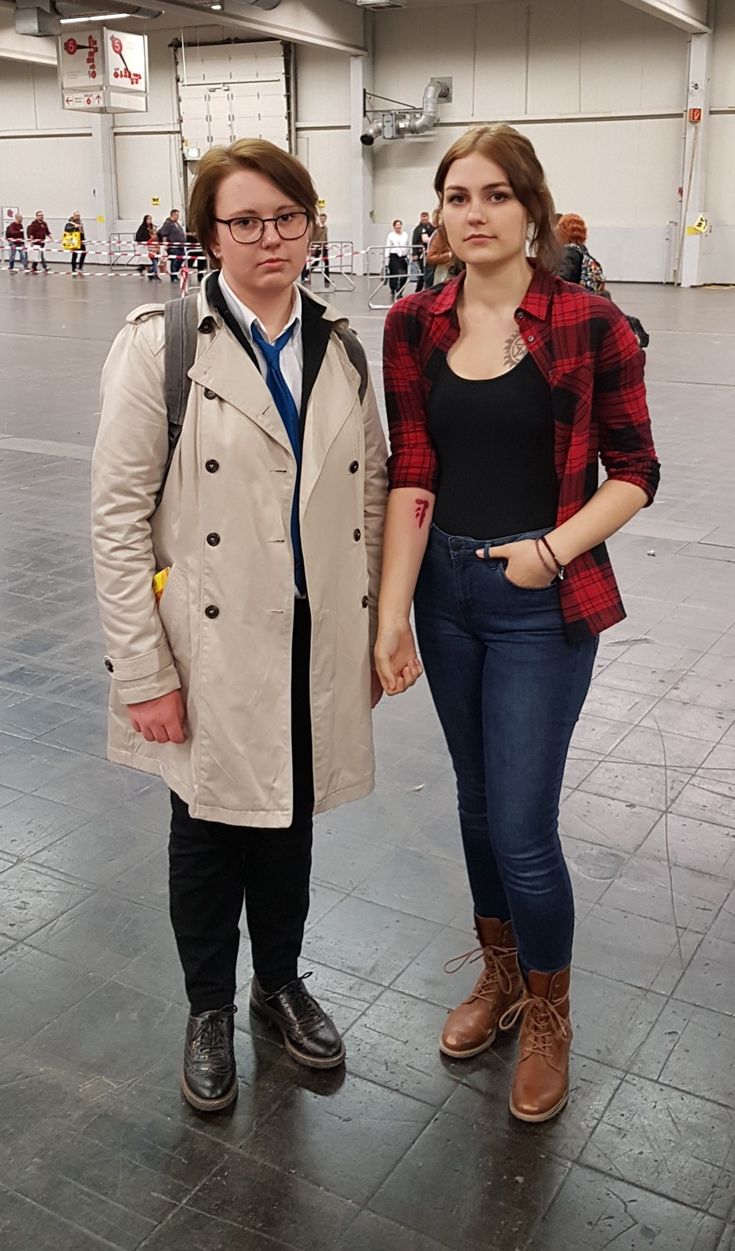 a man and woman standing next to each other in an indoor area with people walking around