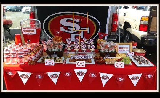 a table topped with lots of food next to a football themed sign and desserts