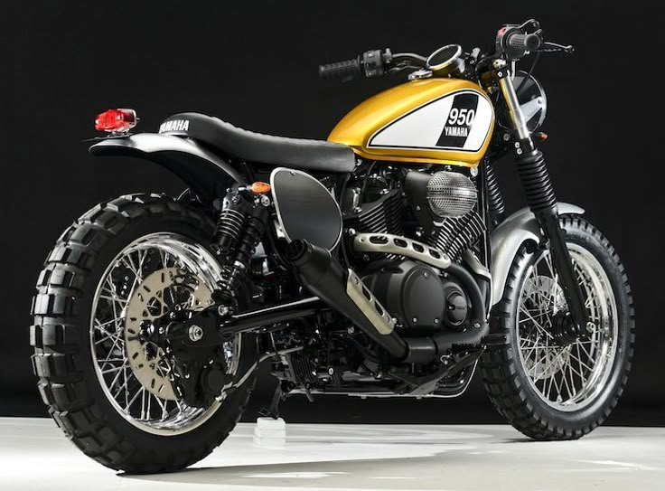 a yellow and black motorcycle parked on top of a white floor in front of a black background