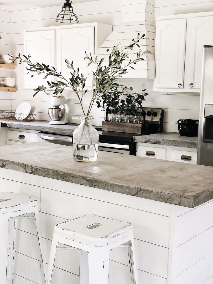 a kitchen counter with two stools and a vase filled with flowers on top of it