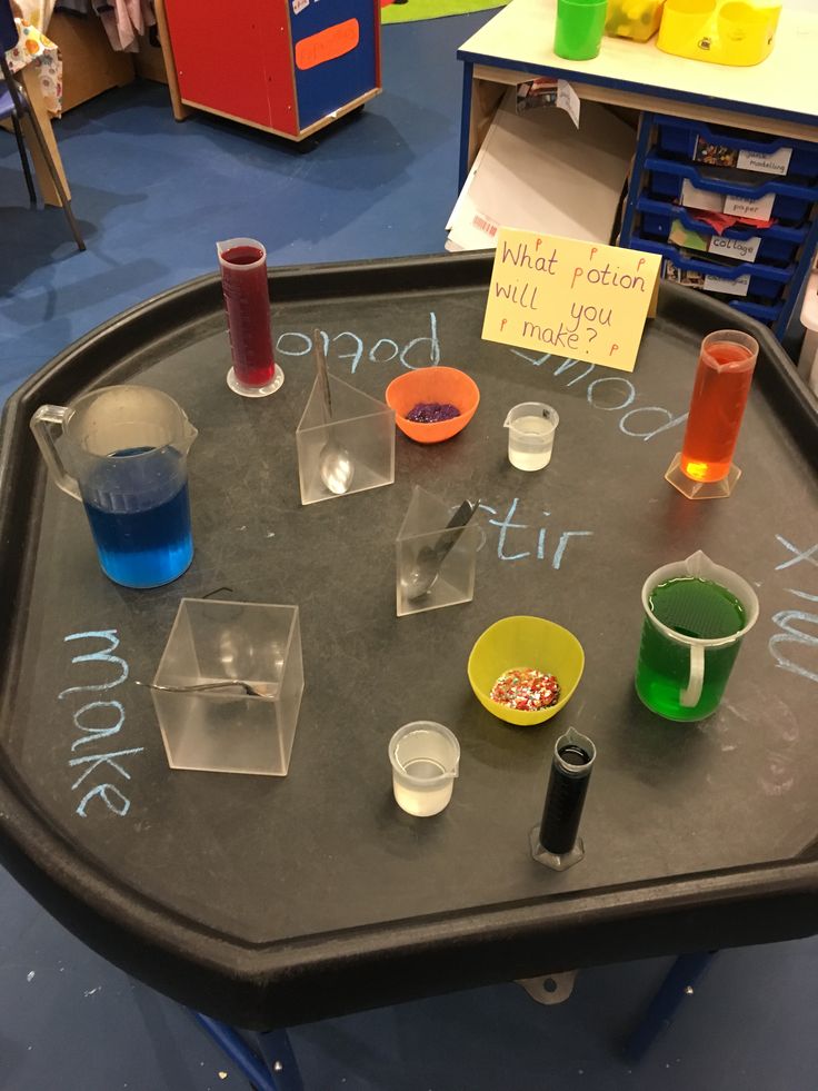 a black table topped with lots of different colored liquids and beaks on it's surface