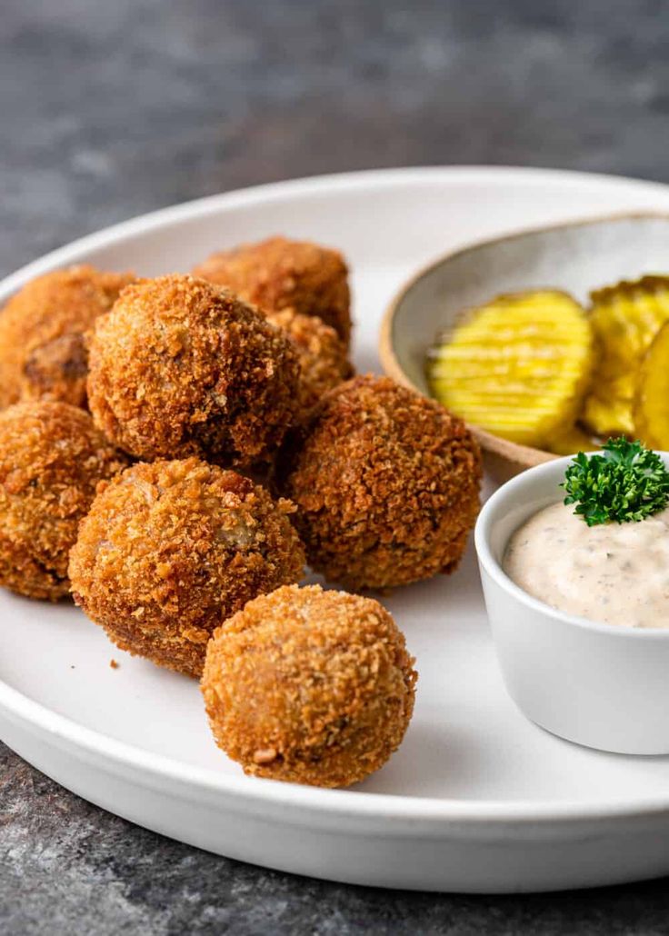 a white plate topped with tater tots next to a bowl of dipping sauce