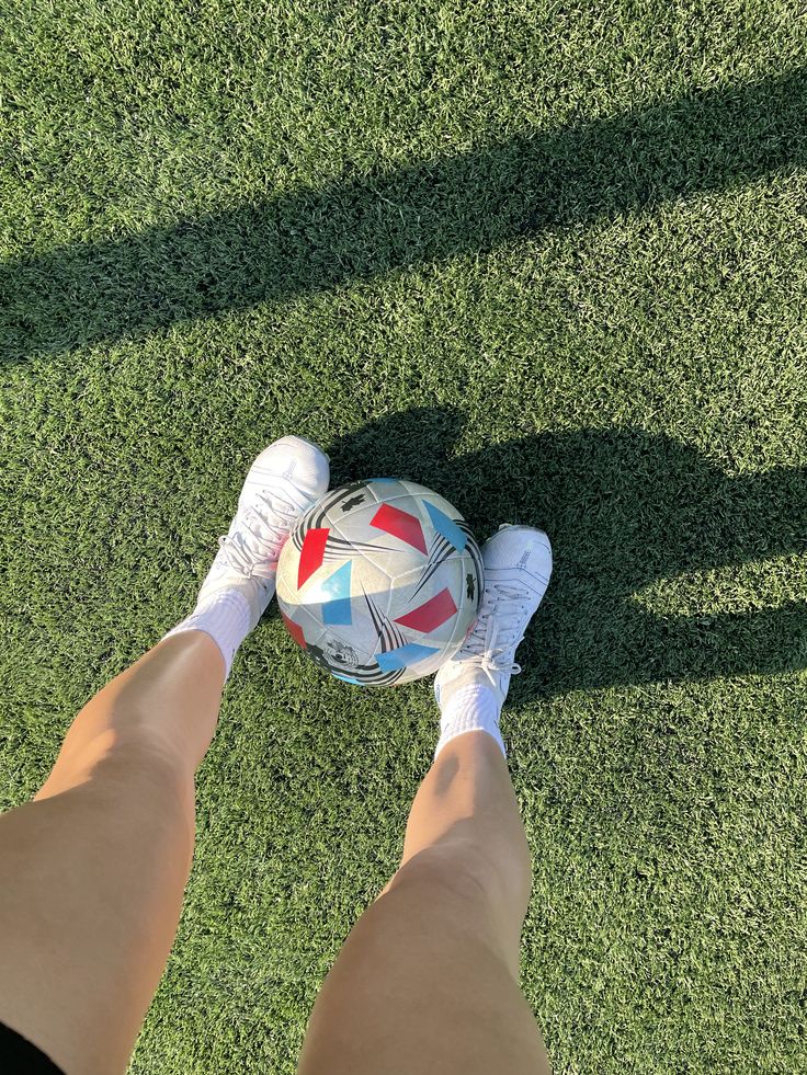 a person standing on top of a lush green field holding a soccer ball in their hands