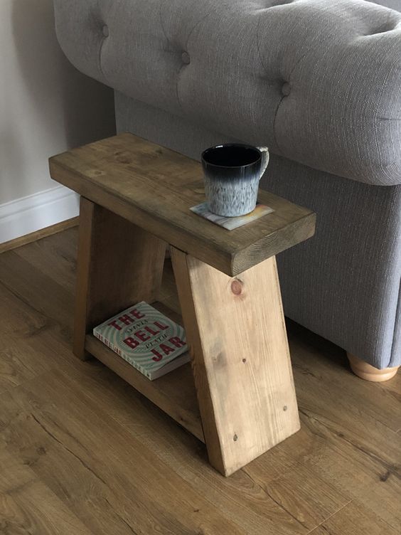 a small wooden table sitting on top of a hard wood floor next to a gray couch