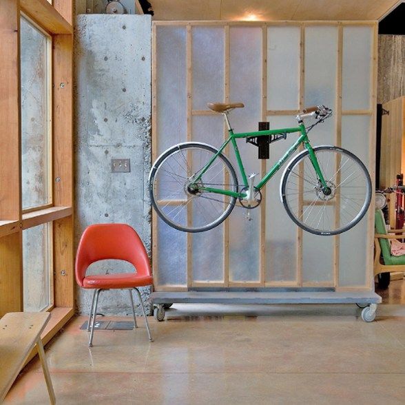 a green bike mounted to the side of a wall next to a chair and table