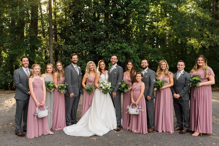 a group of people standing next to each other in front of some trees and bushes