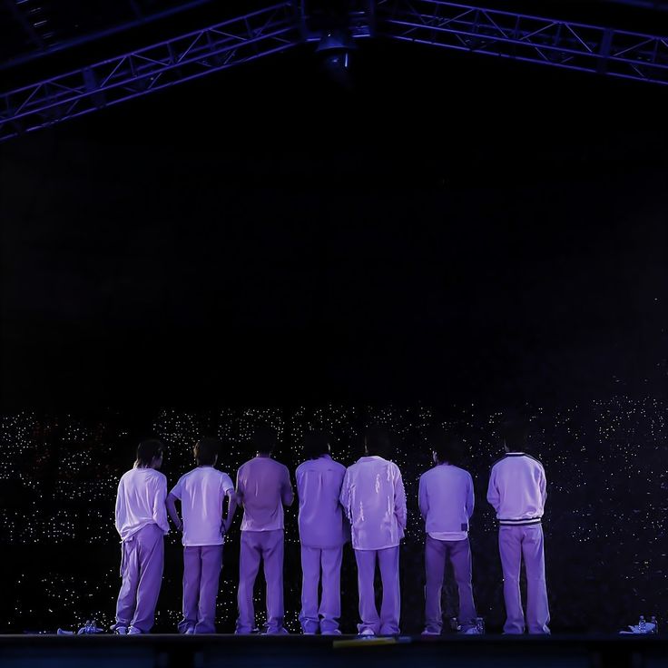 five men standing on stage with their backs to the camera