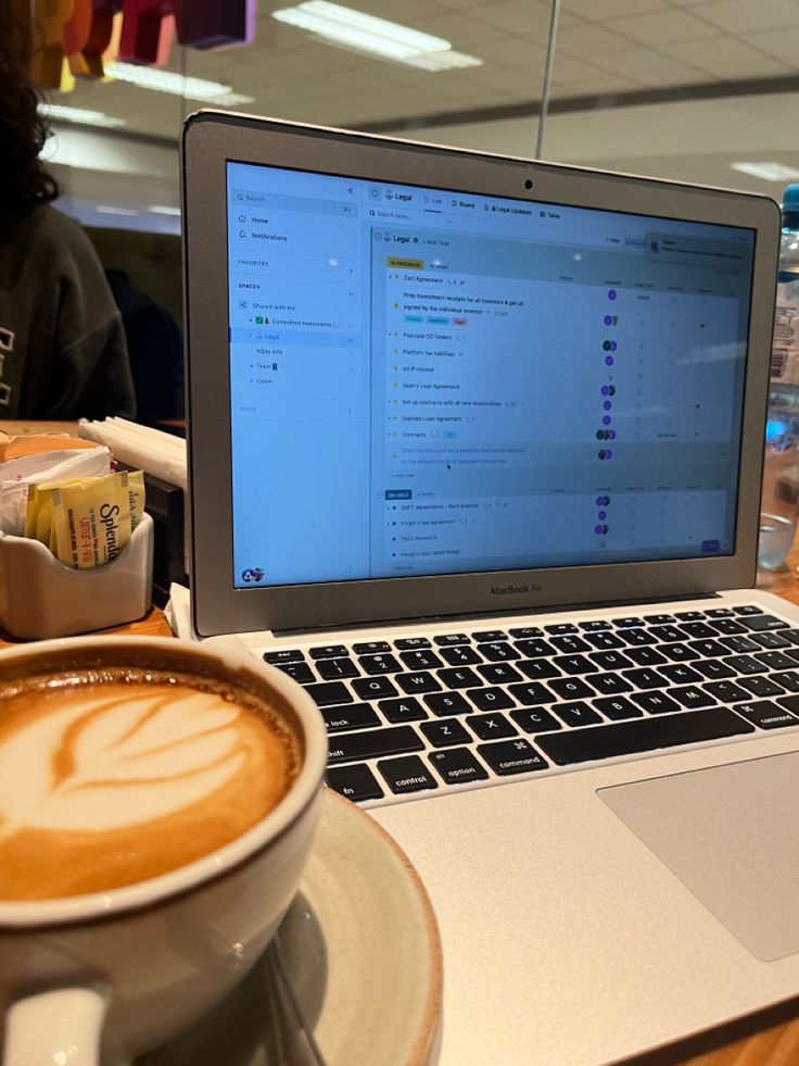 an open laptop computer sitting on top of a table next to a cup of coffee