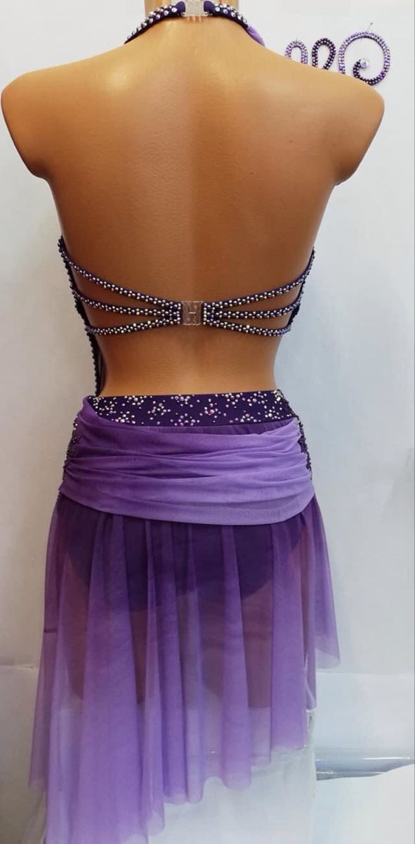 the back of a woman's purple and white dress with beads on it, in front of a mannequin