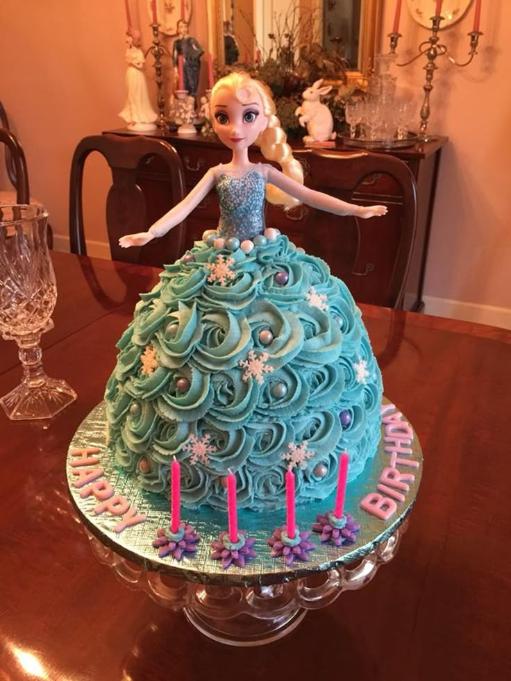 a cake shaped like a princess with blue frosting and pink candles on the top