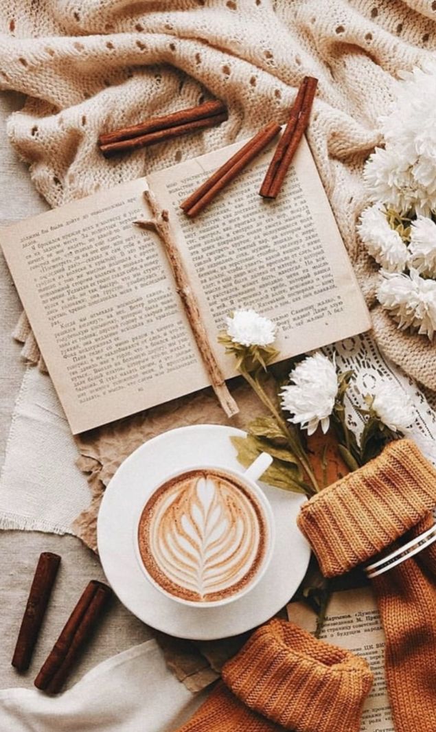 a cup of coffee sitting on top of a table next to an open book