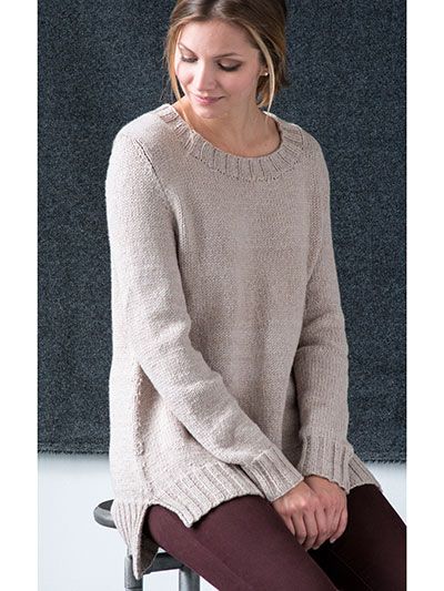 a woman sitting on top of a stool in front of a black wall wearing a sweater and leggings