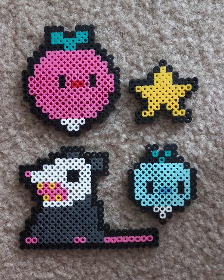 three pieces of perler bead art sitting on top of a carpet next to each other