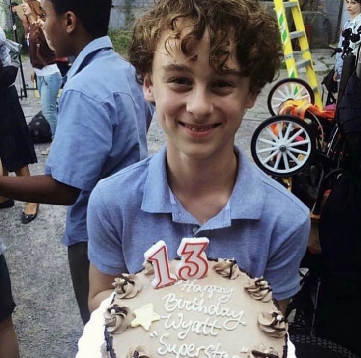 a young boy holding a birthday cake with frosting and icing on the top