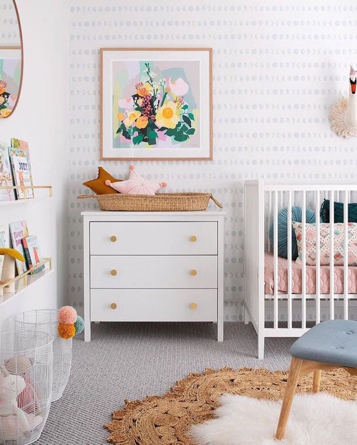 a baby's room with white furniture and flowers on the wall, rugs