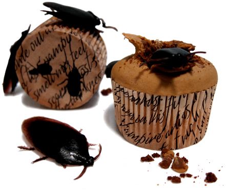 two cupcakes with bugs on them sitting next to each other in front of a white background