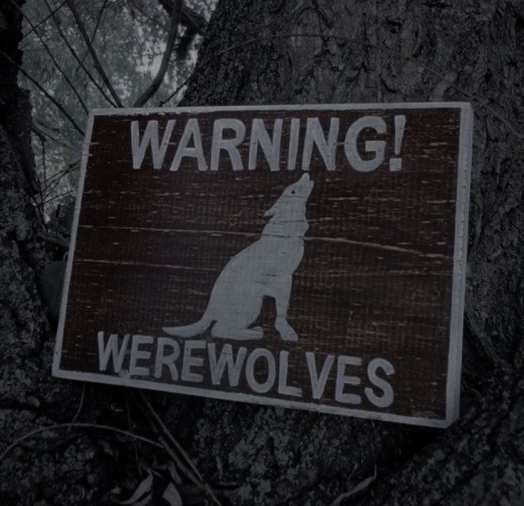 a sign that says warning werewolvess on it in front of a tree with leaves