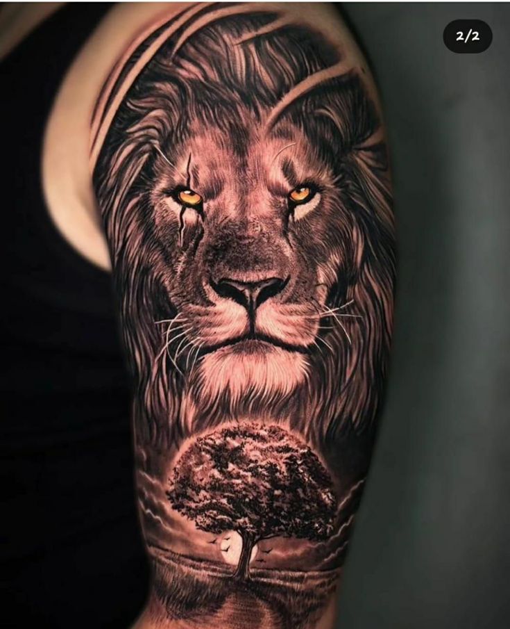 a man's arm with a lion and tree tattoo on the left side of his arm