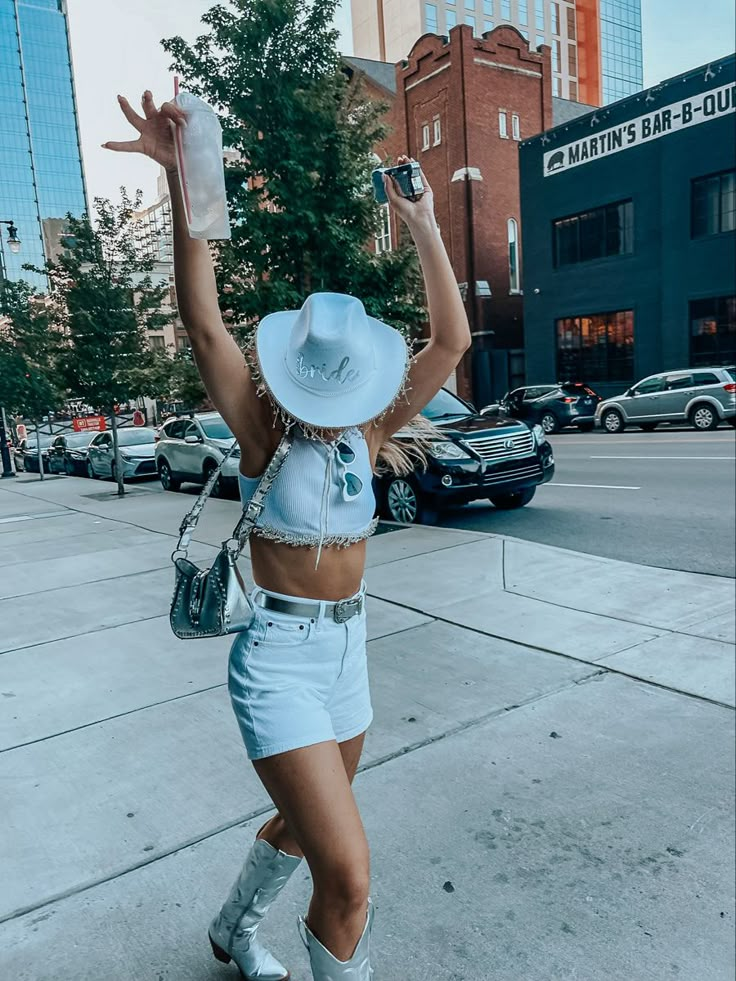 a woman in short shorts and cowboy hat walking down the street