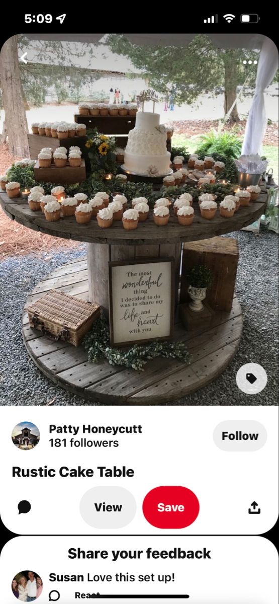 a wooden table topped with cupcakes covered in frosting next to a sign