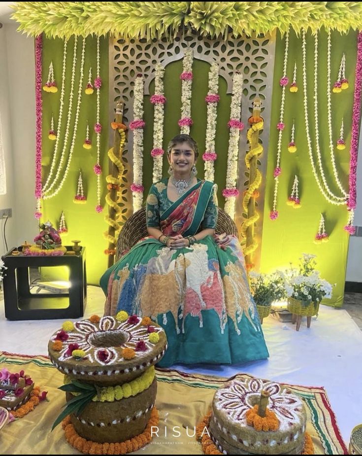 a woman sitting on top of a chair in front of some decorated cakes and flowers