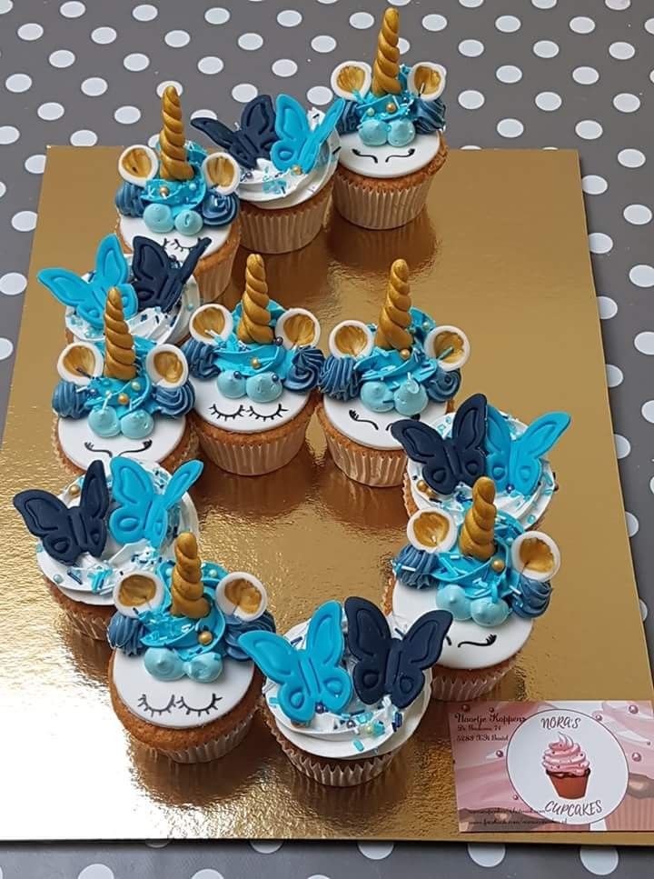 cupcakes decorated with blue and gold icing are arranged in the shape of a number