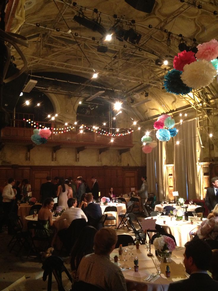 people sitting at tables in a large room with balloons and lights hanging from the ceiling