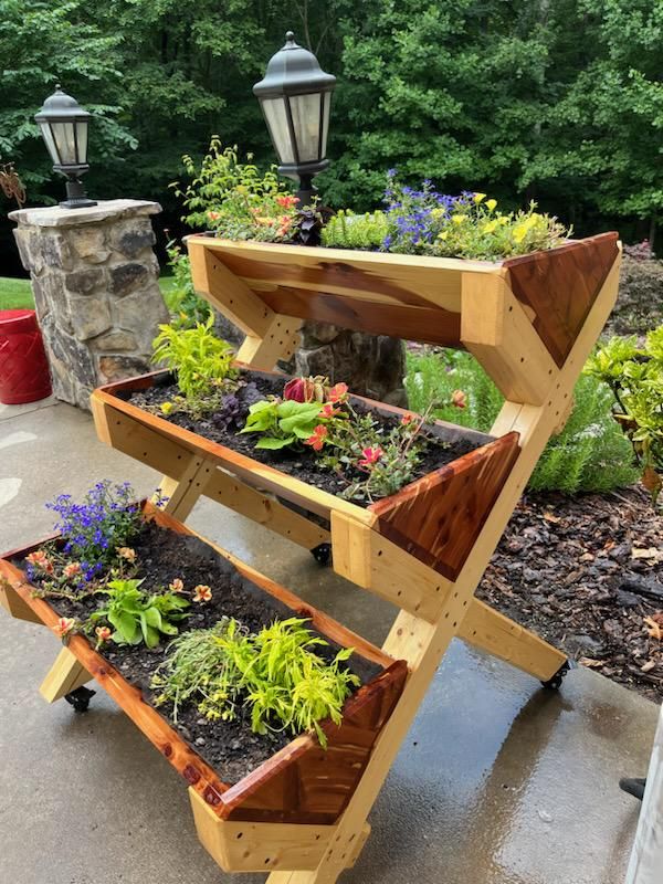 three tiered planter on wheels with plants growing in the bottom and below it