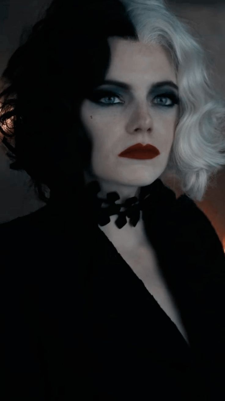 a woman with white hair and black makeup is posing for a photo in the dark