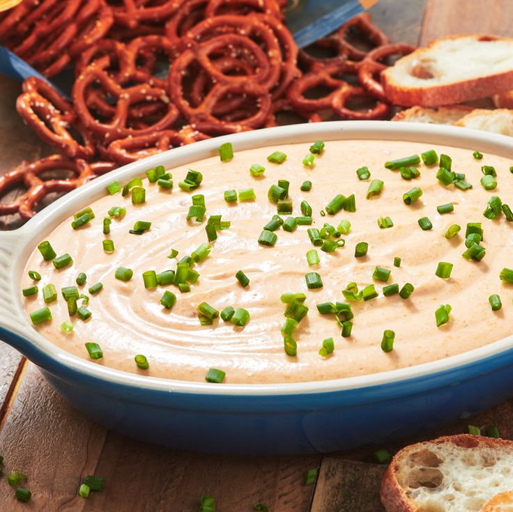 a blue dish filled with dip surrounded by pretzels