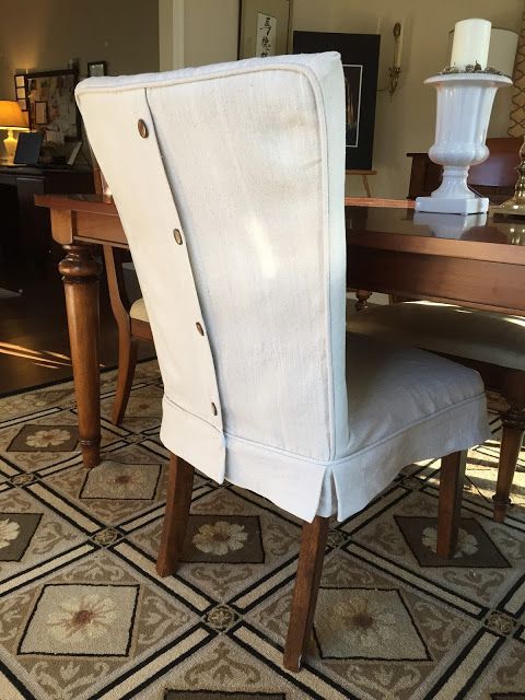 a dining room table with a white chair on top of it and a vase in the background