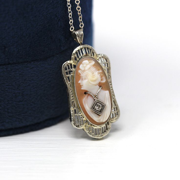 "Beautiful vintage circa 1930s Art Deco era 14k white gold cameo necklace! This stylish pendant features a carved shell cameo, in an intricate filigree setting. The cameo is depicted wearing a Habillé style genuine diamond necklace, and the charm is shown modeled on a brand new 20\" sterling silver chain. A timeless cameo necklace, from the 1930s!  ERA - Circa 1930s - Art Deco METAL / MATERIAL - 14k white gold pendant, shell, genuine diamond (approx. .02 CT) MARKINGS / HISTORY - There are no mar Victorian Necklace With 17 Jewels In Oval Pendant, Victorian White Gold Pendant Necklace, Art Deco White Gold Round Necklaces, Antique White Gold Pendant Necklace, Antique White Gold Filigree Necklace, Classic Pendant Necklace With Filigree, Antique White Gold Necklace With Filigree, Classic Hallmarked Pendant Jewelry, Art Deco Round Necklace For Anniversary