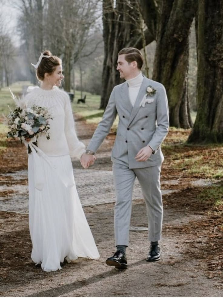 a bride and groom walking down a path holding hands