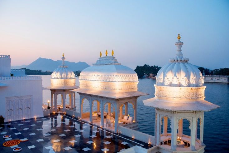 an outdoor gazebo next to the water with lights lit up on it's sides