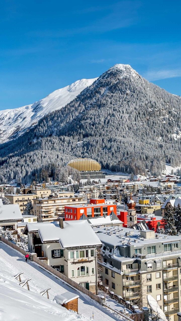 a city with mountains in the background and snow on the ground around it's edges