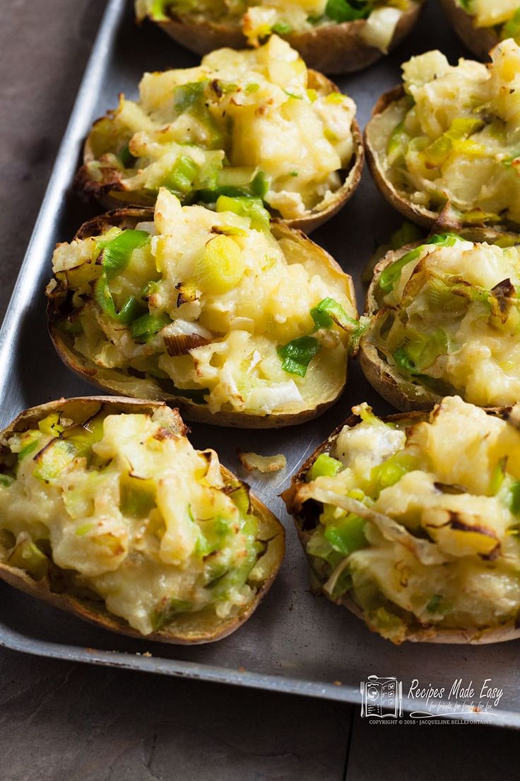 baked potatoes with green onions and cheese on a baking sheet, ready to be eaten