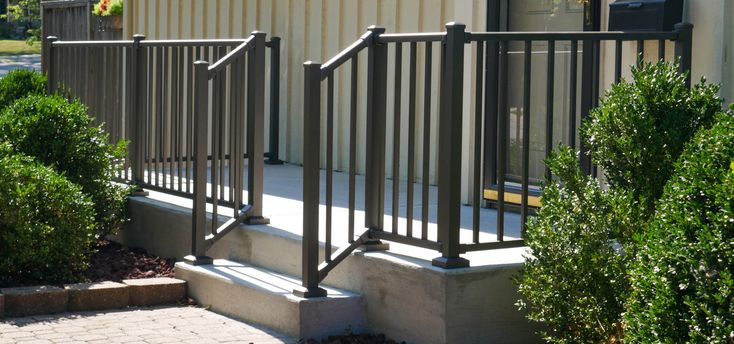 an outside view of a building with metal railings and bushes on the side walk