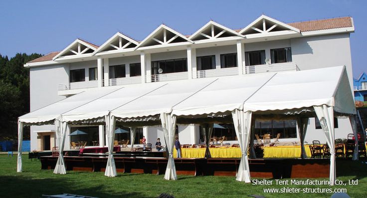 a large white building with lots of tables and umbrellas on the grass outside it