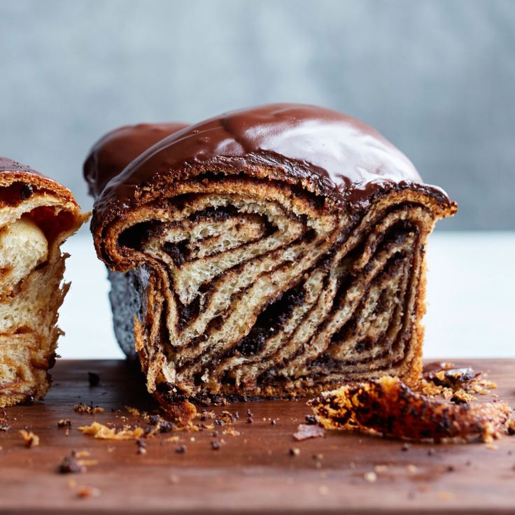 a chocolate roll cut in half on a wooden cutting board with one slice taken out