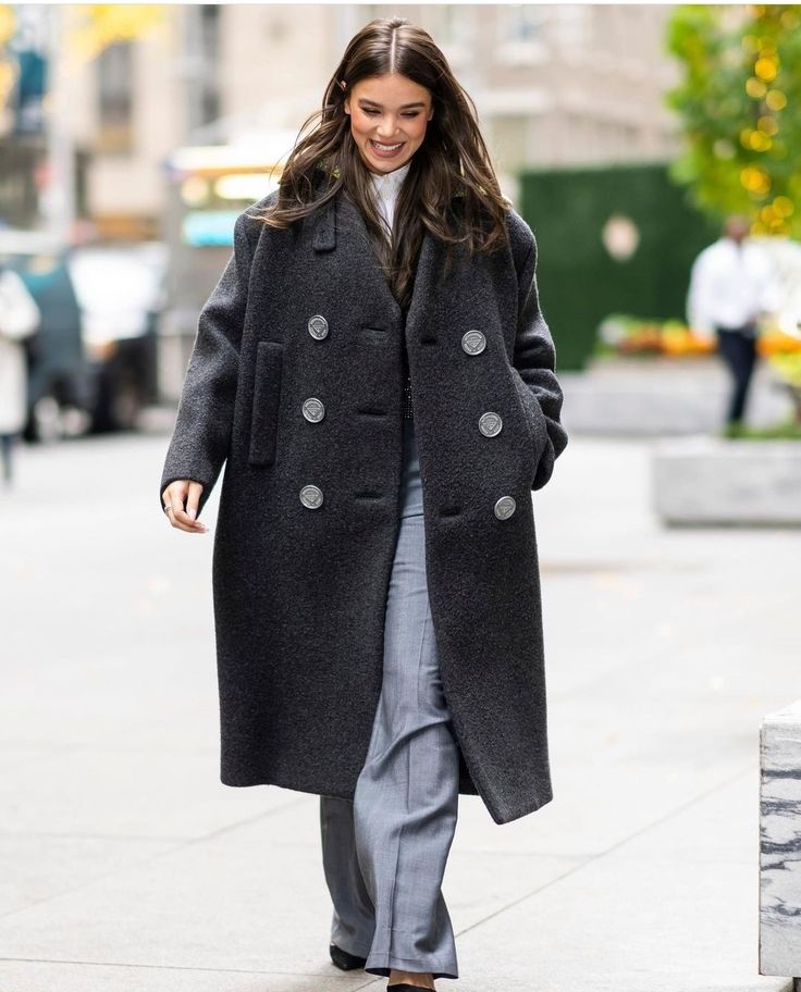 a woman is walking down the street wearing a coat