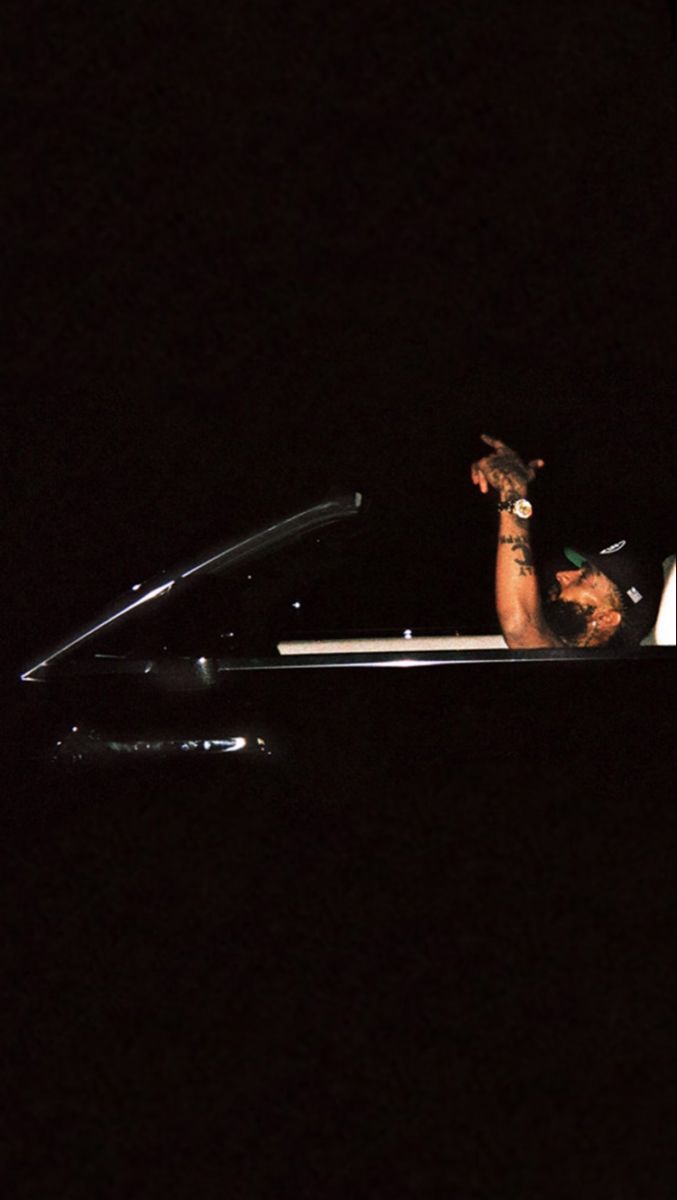 a man in a boat at night with his arm out to the side, pointing