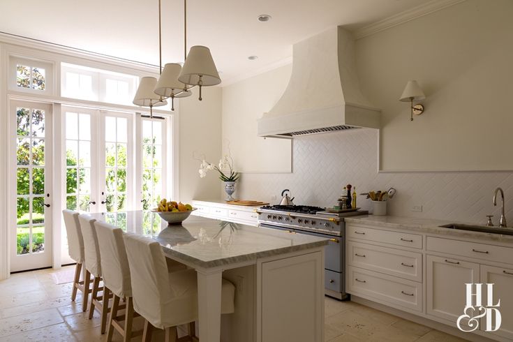 a large kitchen with white cabinets and marble counter tops, an island in the middle