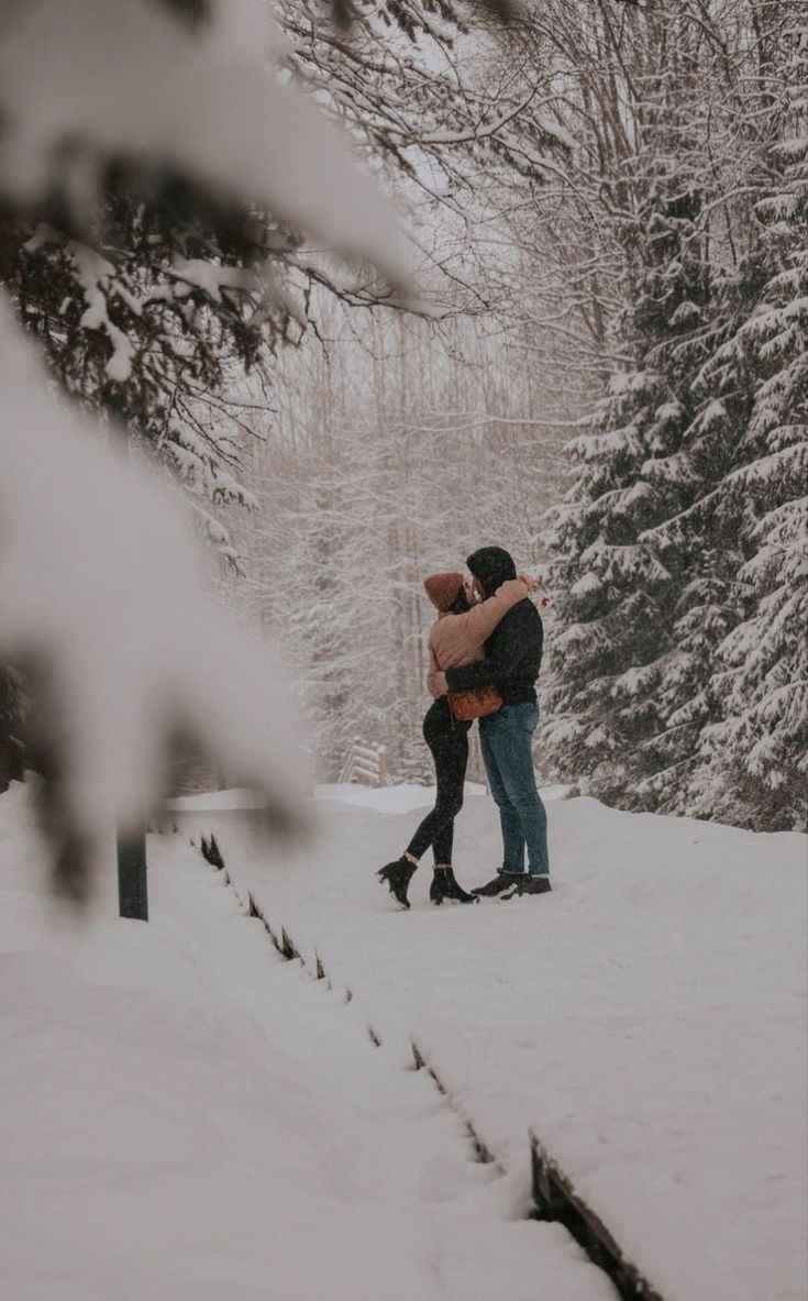 two people standing in the snow hugging each other