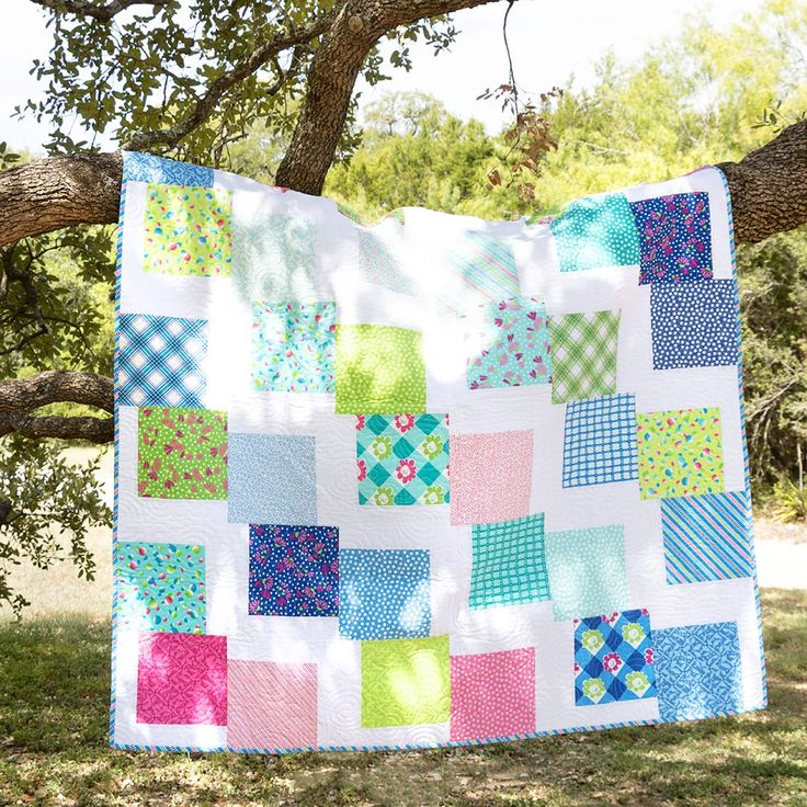 a patchwork quilt hanging from a tree