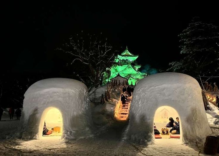 an igloose is lit up at night with people sitting in the doorway