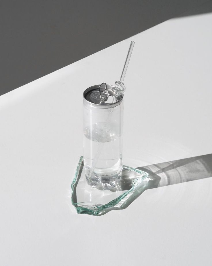 a glass filled with water sitting on top of a white table next to a toothbrush