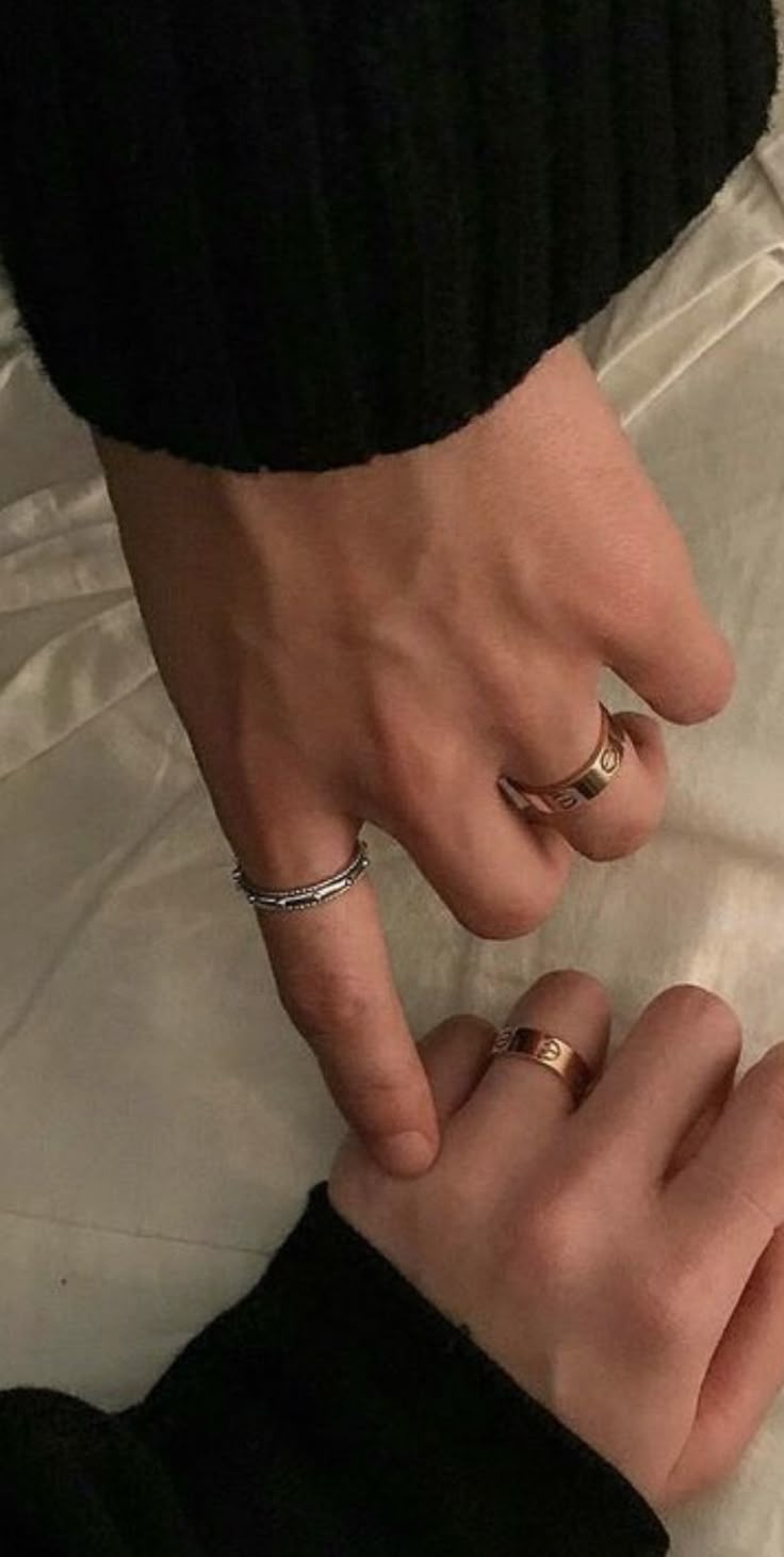 two people with wedding rings on their fingers, one holding the other's hand