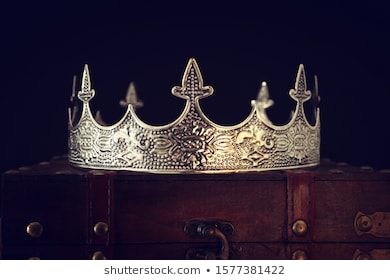 a silver crown sitting on top of a wooden trunk in front of a black background